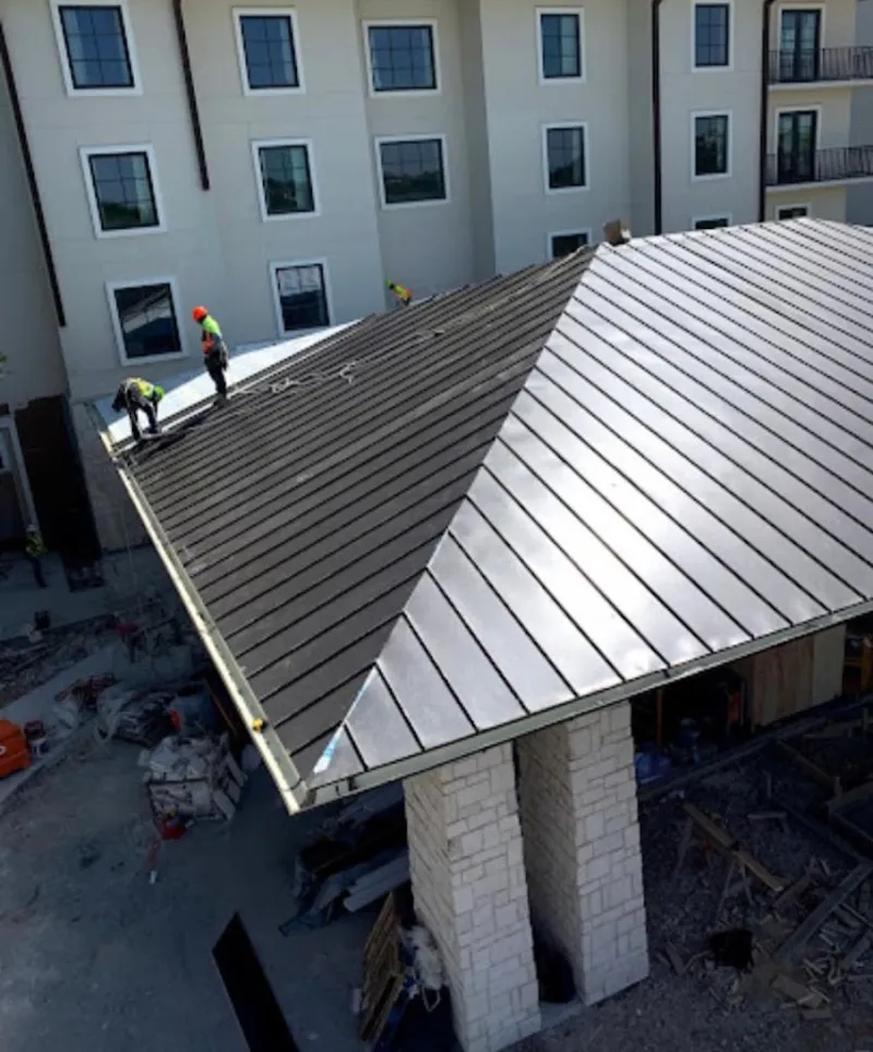 Crew installing standing seam metal roof panels on a commercial project in South Orange Village